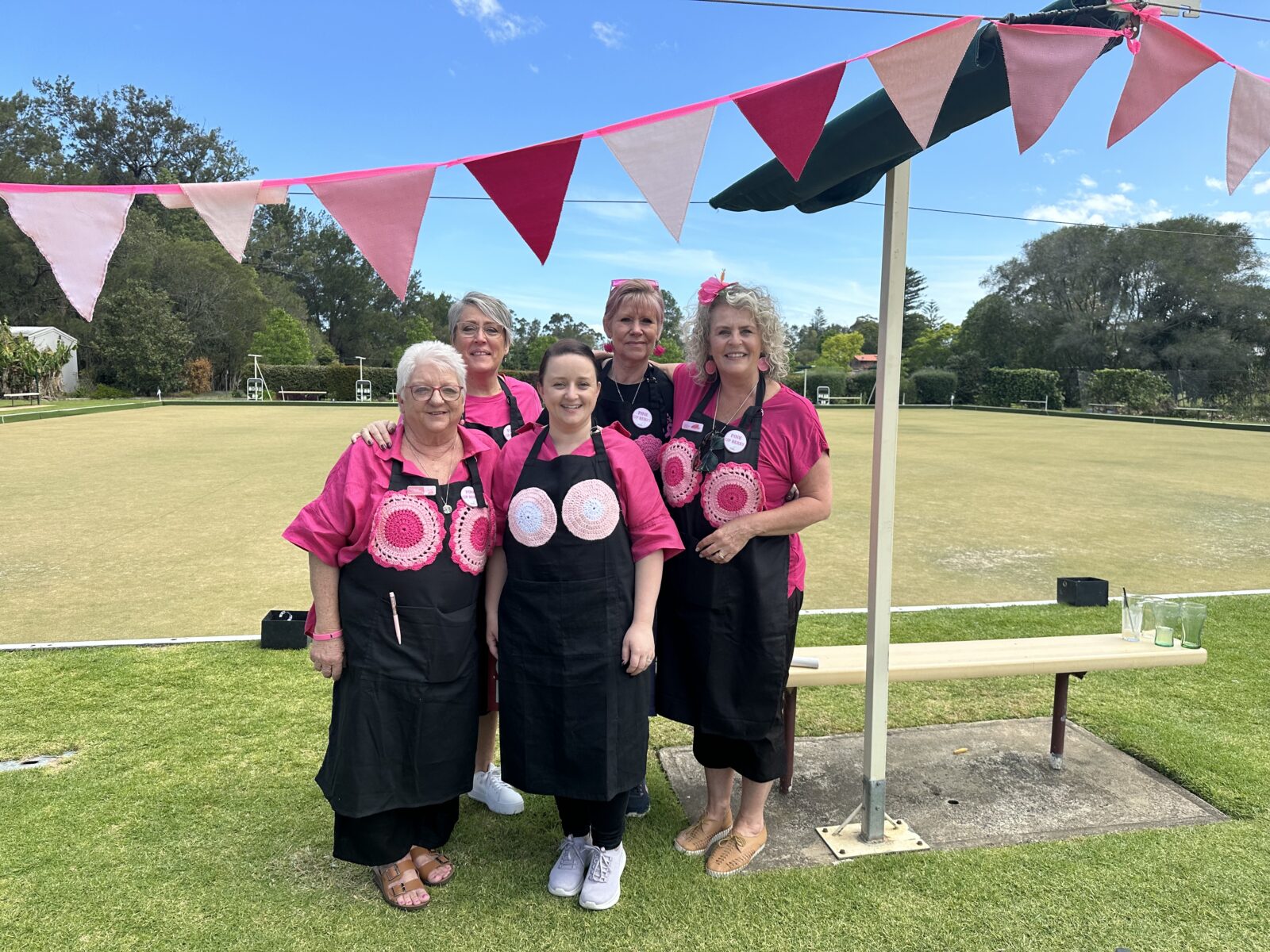 Group of fundraisers at Pink Up Berry standing on bowling greens wearing pink.