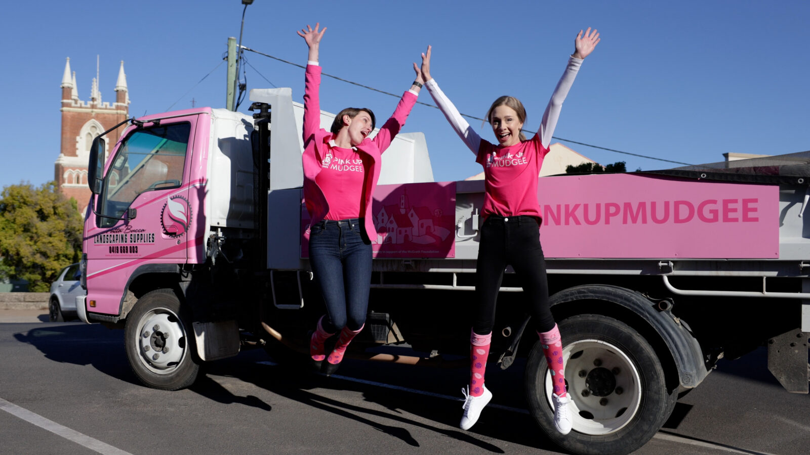 Pink Up Mudgee fundraisers jumping in the air in front of pink truck.
