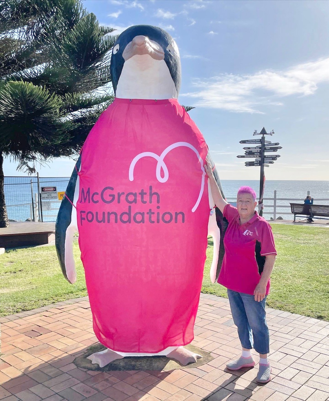 Pink Up Penguin fundraiser standing next to penguin model wearing a McGrath Foundation cover.